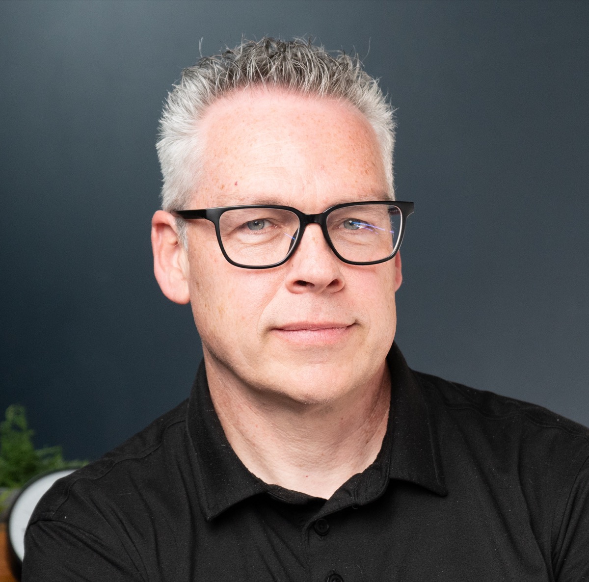 Cameron Armstrong wearing glasses against a dark background