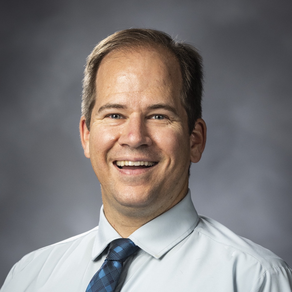 Joshua Sears smiling in a shirt and tie